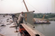 1990. július 23. Építik a korlátot a Hárosi hídon. A terveknek megfelelő ütemben épül az MO-ás körgyűrű. A 6-os főútvonalat és az M5-ös autópályát összekötő 14 km-es szakaszból 3,5 km-t már átadtak, a többit október végén adják át a forgalomnak. Jelenleg két Duna-hídon dolgoznak az építők, a Hárosi hidat szigetelik, betonozzák, a Haraszti hídnál a környezetvédelmi előírásoknak megfelelően az olajfogó csapdákat építik, illetve kotorják és iszapolják a hídkörnyéki folyómedret.
