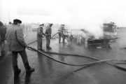 Budaörs, 1990. január 23. Kiégett autót oltanak a tömeges baleset helyszínén az M1-M7-es autópálya közös bevezető szakaszán, a 7-es és 12-es kilométerkő közötti szakaszon. A csúszós, nyálkás úton - amelyen a köd miatt 50-100 méterre csökkent a látótávolság - mintegy 200 személy- és teherautó, valamint kamion ütközött egymásnak. A balesetnek 1 halálos áldozata volt, 14-en súlyosan, 19-en könnyebben sérültek. 10 személyautó kiégett, az egymásba torlódott teher- és személyautók zöme pedig súlyosan megrongálódott. Az anyagi kár jelentős.