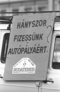  Budapest, 1989. április 17. Egy autóra erősített transzparens a tiltakozó demonstráción, melyet a KIOSZ Személy- és Teherfuvarozók Országos Szakmai Tagozata szervezett az autópályahasználati-díj bevezetése ellen a fővárosban. A felvonuló személygépkocsik és teherautók 20 km-es sebességgel haladtak, ezzel demonstrálva az autópályahasználati-díj bevezetésének kedvezőtlen, forgalomlassító hatását a városi forgalomra. A közel 100 gépkocsiból álló konvoj - rendőri kísérettel - a Hősök terétől vonult a Dózsa György úton és a Váci úton át a Parlamentig. Itt adták át a miniszterelnöknek címzett tiltakozásukat és állásfoglalásukat Kiss Elemérnek, a Minisztertanács hivatala elnökhelyettesének, aki fogadta a fuvarosok megbízottait. 